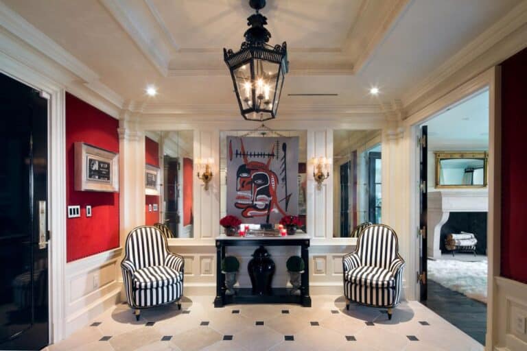 Luxurious home interior with elegant decor, black and white striped armchairs, a contemporary chandelier, and vibrant artwork in a sophisticated entryway.