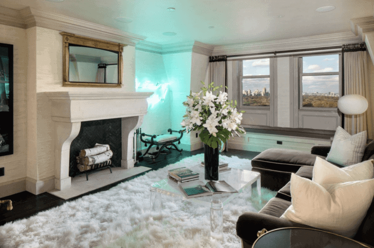 Elegant living room with contemporary decor, large windows offering city views, cozy fireplace, floral centerpiece, and plush seating, showcasing modern interior design.