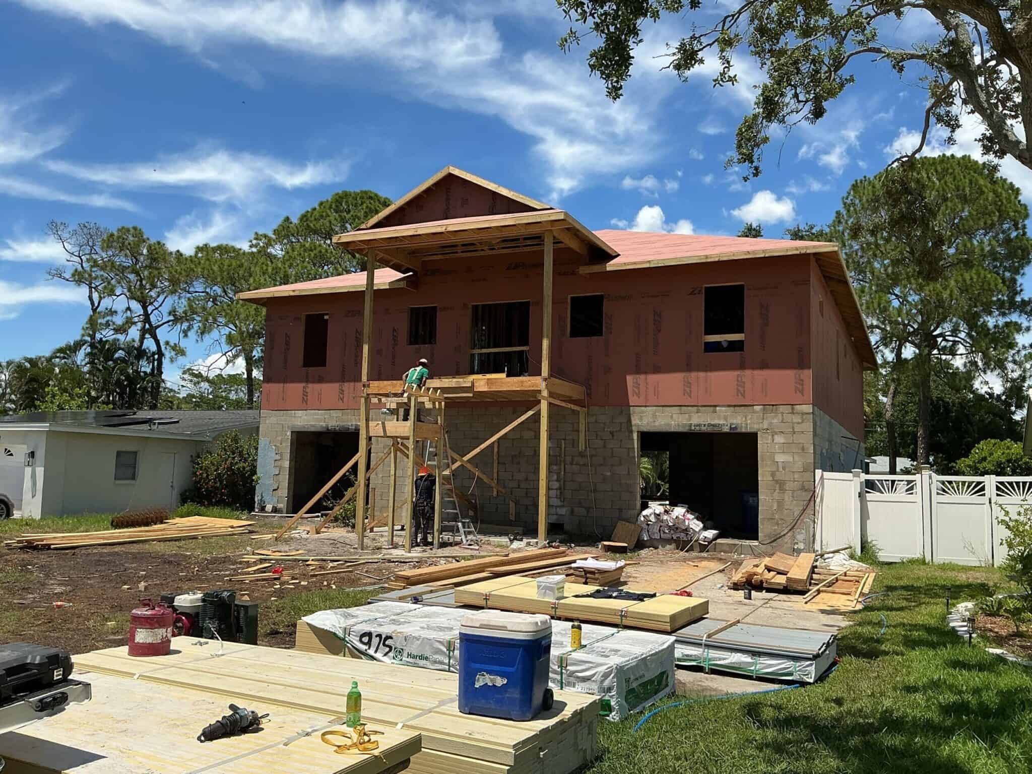 Home 11 New residential construction in progress with workers assembling the second story, using framing materials under a bright blue sky, showcasing modern home building and construction expertise.