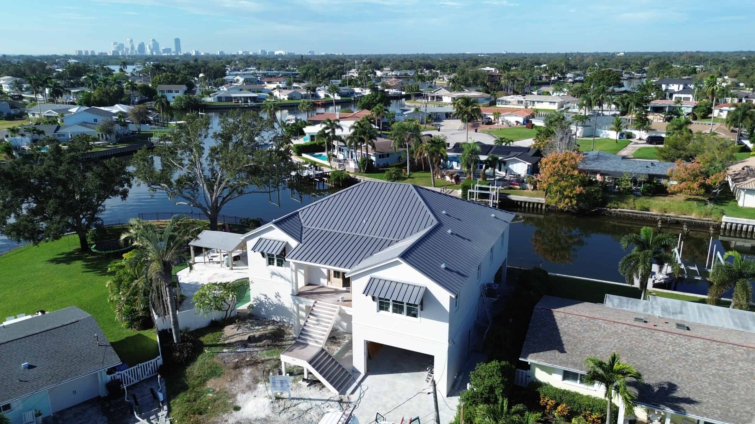 Modern waterfront home with custom roofing and innovative design, located in a scenic neighborhood with lush greenery and water views; a showcase of luxury real estate and architectural excellence.