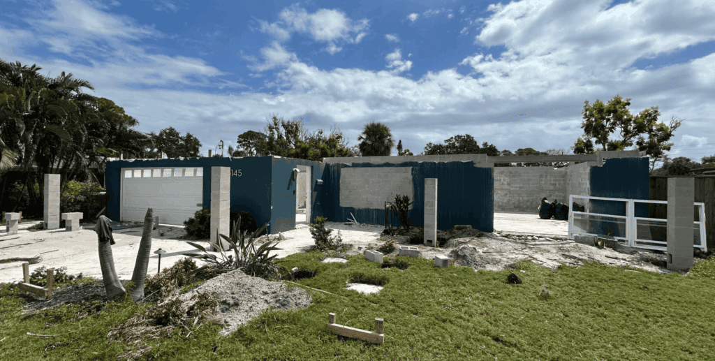 Building under construction with partially finished walls, garage, and front yard, highlighting residential real estate development, construction progress, and innovative building solutions by Iridium Development Inc.