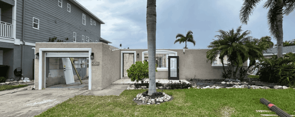 A new home exterior with ongoing construction, featuring landscaped garden, palm trees, and modern architecture for contemporary living.
